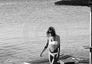 Amazing girl with sunglasses in a white swimsuit  walking on the rocky beach. Apulia, Salento, Italy