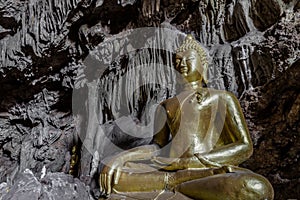 Amazing gold buddha statue in beautiful cave, holy natural buddhist sanctuary in Thailand