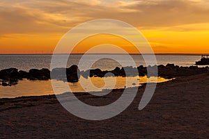 Amazing golden sunset on an empty beach. Orange and red sky shades. Deserted seaport on the shore post card