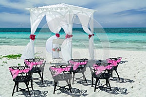 Amazing gorgeous inviting view of wedding decorated gazebo with old vintage black metal chairs on the beach