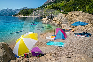 Amazing gravelly beach with colorful parasols and towels