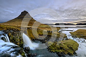 Amazing Icelandic landscape at the top of Kirkjufellsfoss waterfall with Kirkjufell mountain in the background