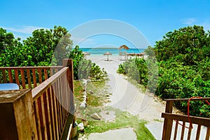 Amazing inviting walk way from a beach bar leading to beautiful white sand beach and ocean at Las Brujas island, Cuba photo
