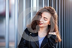 Amazing joyful pretty girl with long brunette hair. posing outdoor. leather jacket,brunette hair, bright red lips Close up fashion