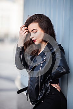 Amazing joyful pretty girl with long brunette hair. posing outdoor. leather jacket,brunette hair, bright red lips Close up fashion