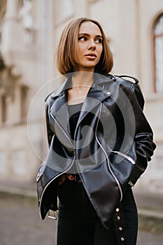 Amazing joyful pretty girl posing outdoor. leather jacket,brunette hair, bright red lips Close up fashion street stile portrait