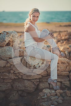 Amazing lady blond woman in light white stylish clothes posing on sea side beach air.Sparkler girl looking to camera on ancie photo