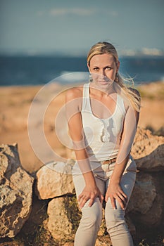 Amazing lady blond woman in light white stylish clothes posing on sea side beach air.Sparkler girl looking to camera on ancie photo