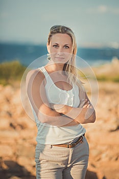 Amazing lady blond woman in light white stylish clothes posing on sea side beach air.Sparkler girl looking to camera on ancie photo