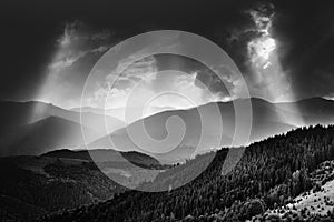 Amazing landscape of mountains hills in sunbeam and cloudy sky in black and white shadow light.