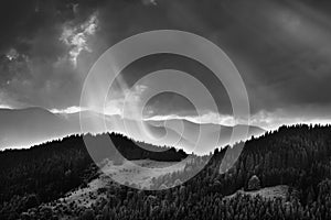 Amazing landscape of mountains hills in sunbeam and cloudy sky in black and white shadow light.