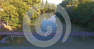 Amazing landscape young couple blond man and brunette woman lie on suspension bridge over river