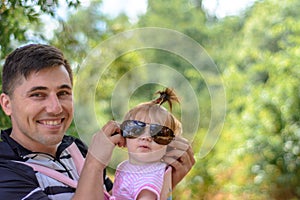 Amazing little girl is playing with sunglasses with her father