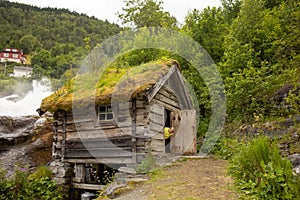 Amazing little wooden small house next to a waterfall on the dock of Hellesylt, child playing in the house