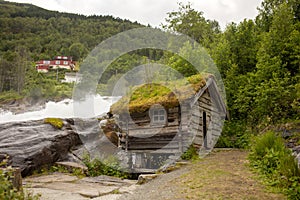 Amazing little wooden small house next to a waterfall on the dock of Hellesylt, child playing in the house