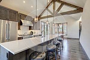 Amazing modern and rustic luxury kitchen with vaulted ceiling and wooden beams, long island with white quarts countertop