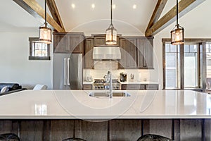 Amazing modern and rustic luxury kitchen with vaulted ceiling and wooden beams, long island with white quarts countertop