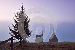 Amazing mountain landscape with fog and a haystack in autumn