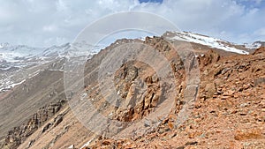 Amazing mountain landscape. Panorama of red rocky cliffs and snow-capped mountains. Blue sky and white clouds. The amazing nature