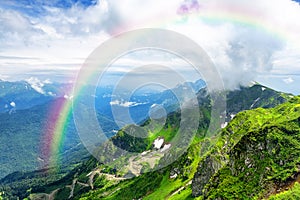 Amazing mountain landscape on sunny summer day with a rainbow in the sky