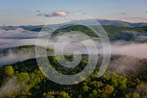 Amazing nature landscape, scenic aerial view of the foggy Carpathian mountains and blue sky with clouds