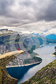 Amazing nature view with Trolltunga and a girl sitting on it. L