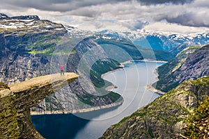 Amazing nature view with Trolltunga and a girl standing on it.