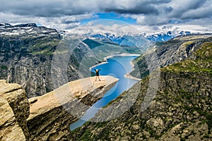 Amazing nature view with Trolltunga and a girl standing on it.