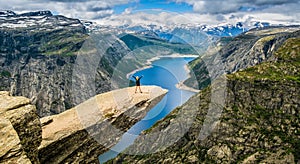 Amazing nature view with Trolltunga and a girl standing on it