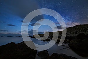 Night sky over a rocky coastline