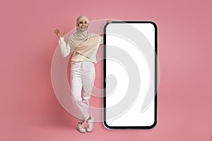 Amazing Offer. Excited Muslim Woman In Hijab Standing Near Big Blank Smartphone