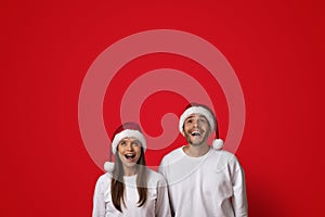 Amazing Offer. Excited Young Couple In Santa Hats Looking Up With Amazement