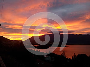 Amazing orange sky over the alpine mountains and the lake Wakatipu in Queenstown