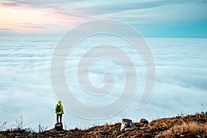 Amazing panorama of clouds floating all over the territory and a persistent boy of 20-25 years stands on a tree stump and enjoys