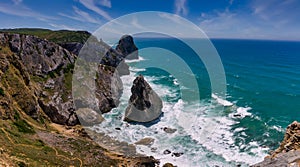 Amazing panorama of Rocky shore  Atlantic Ocean. View of high cliffs, foamy waves and sandy beach. Sunny summer seascape. Portugue photo