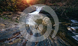 Amazing panoramic landscape mountain river in autumn forest at sunlight. View of stone water rapids and small waterfall.