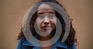 Amazing portrait of happy calm beautiful gen-z mixed race 20-25 woman with curly hair posing at camera slow motion.