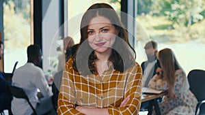 Amazing portrait of successful young 30s brunette Caucasian business woman smiling at camera at light office slow motion