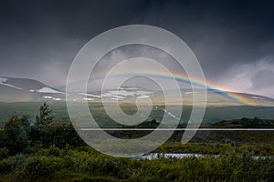 Amazing rainbow in cloudy sky over the tundra landscape on the Arctic Circle line in northern  Norway