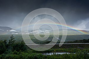 Amazing rainbow in cloudy sky over the tundra landscape on the Arctic Circle line in northern  Norway