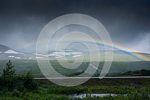 Amazing rainbow in cloudy sky over the tundra landscape on the Arctic Circle line in northern  Norway