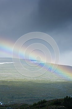 Amazing rainbow in cloudy sky over the tundra landscape on the Arctic Circle line in northern  Norway