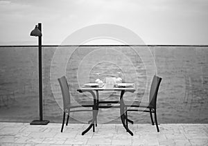 Amazing romantic dinner on the beach. Romance and love, dinning table setup with sea view in cloudy day. Black white photo