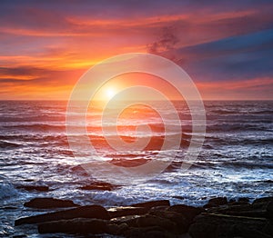 Amazing romantic seascape of ocean coastline at sunset. Landscape of colorful cloudy sky and foamy waves.