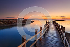 Amazing romantic view from the pier at sunset. Serene landscape on the lake at colorful sunset. Old wooden pier in a fineart photo