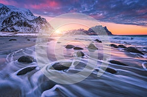 Amazing sandy beach with stones in blurred water at sunset