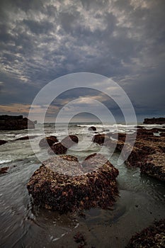 Amazing seascape for background. Beach with rocks and stones. Low tide. Motion water. Cloudy sky. Slow shutter speed. Soft focus.