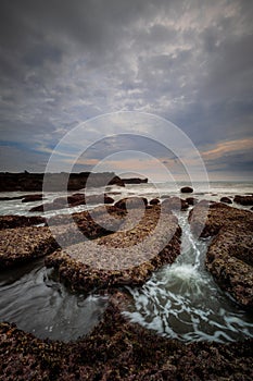 Amazing seascape for background. Beach with rocks and stones. Low tide. Motion water. Cloudy sky. Slow shutter speed. Soft focus.