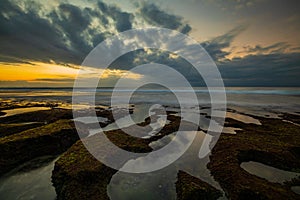 Amazing seascape. Beach with rocks and stones. Low tide. Clear water. Sky reflection in water. Slow shutter speed. Soft focus.