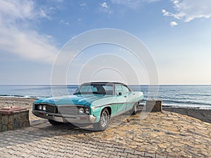 amazing shot of a classic car parked on the beach with blue sky